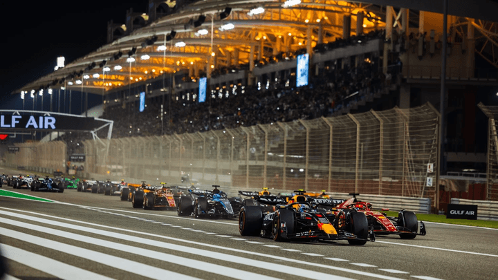 Voitures de Formule 1 en action lors d'une course nocturne avec l'architecture moderne de Bahreïn en arrière-plan