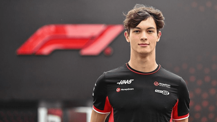 Portrait d'Ollie Bearman en combinaison Haas F1 Team noir et rouge, regardant la caméra avec une expression sérieuse