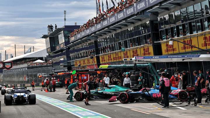 Voitures de Formule 1 alignées dans la voie des stands du circuit d'Albert Park à Melbourne avec les équipes techniques en action