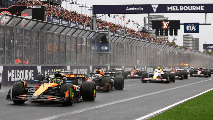Voitures de Formule 1 en action sur le circuit de Melbourne avec les tribunes en arrière-plan