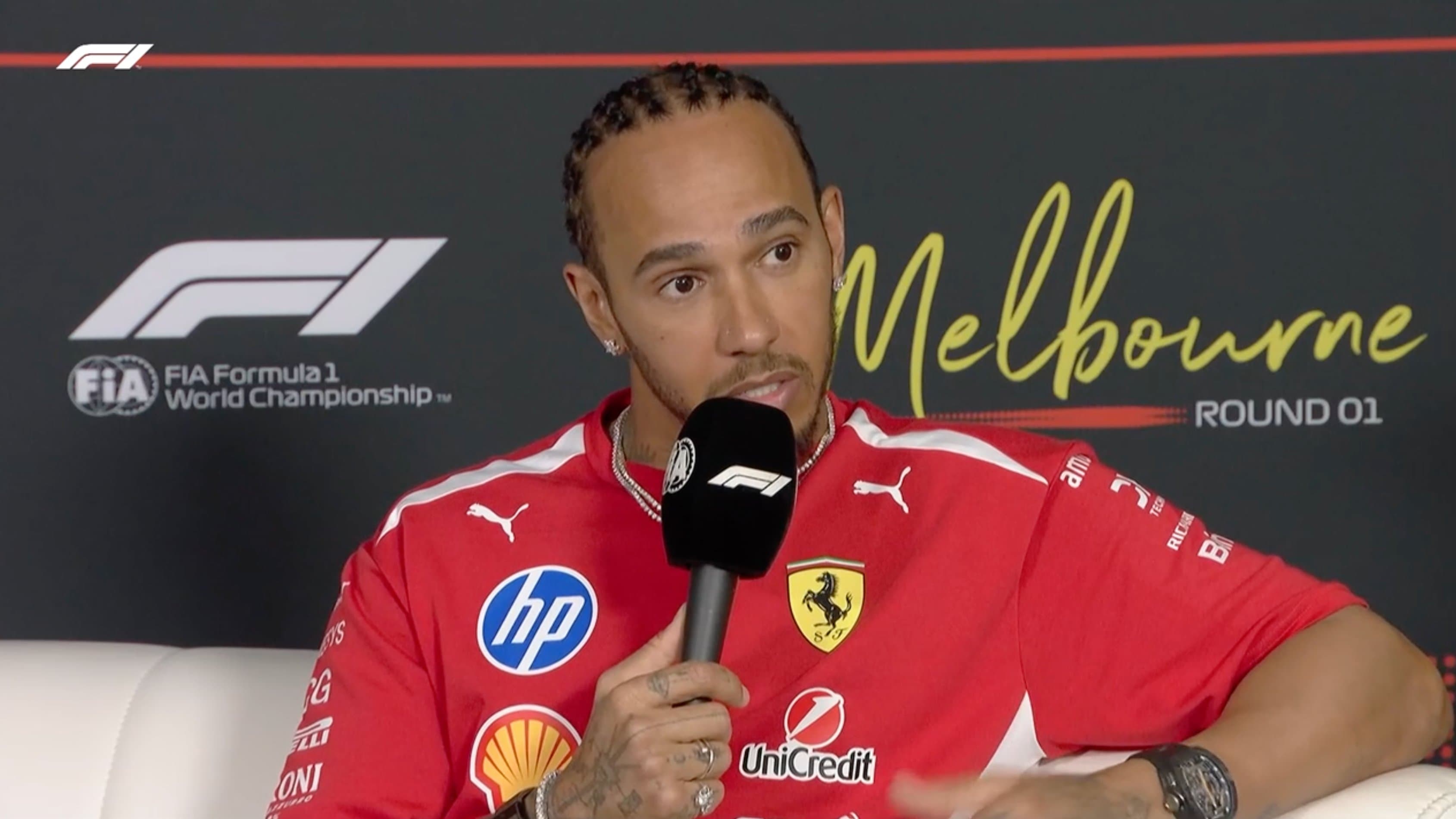 Lewis Hamilton lors d'une conférence de presse, portant sa combinaison Ferrari rouge