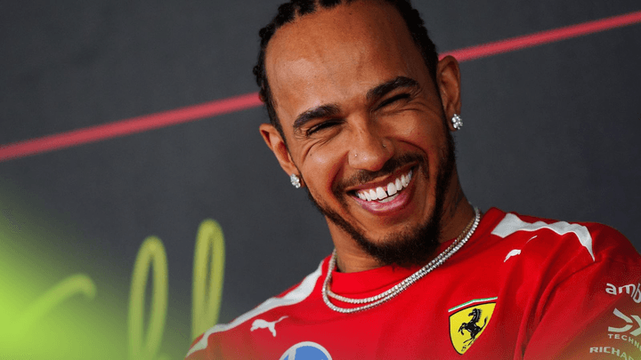 Lewis Hamilton souriant en combinaison Ferrari rouge lors d'une conférence de presse de Formule 1
