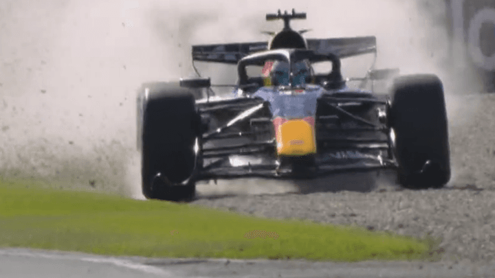 Monoplace de Formule 1 Red Bull sortant de piste dans l'herbe avec projection de terre et débris