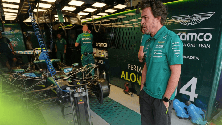 Voiture Aston Martin F1 verte entourée de mécaniciens et de Fernando Alonso dans les stands