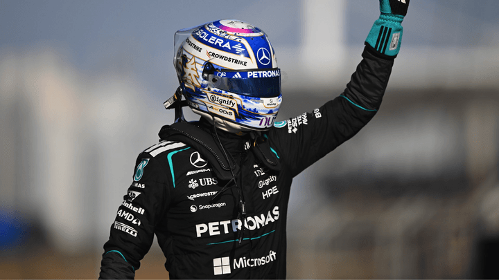 Pilote de F1 en combinaison Petronas levant le bras en signe de victoire après sa pole position