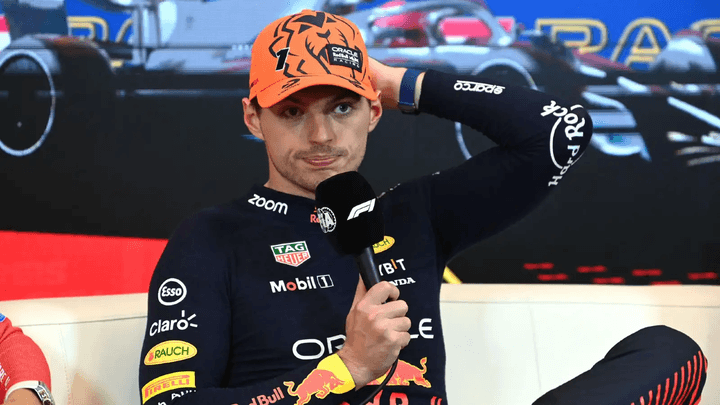 Max Verstappen en conférence de presse, tenant un micro et s'exprimant devant les médias