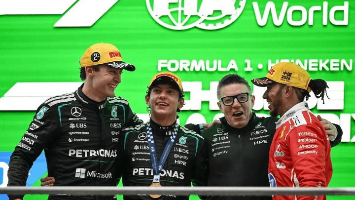 Podium du Grand Prix avec quatre pilotes de F1 célébrant, incluant un pilote Mercedes et un Ferrari
