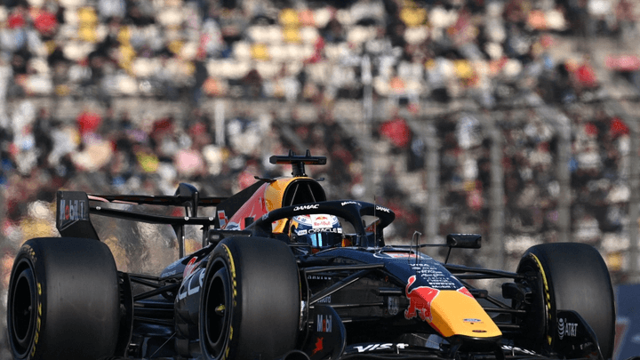 Max Verstappen au volant de sa Red Bull RB19 en action sur circuit avec tribunes en arrière-plan