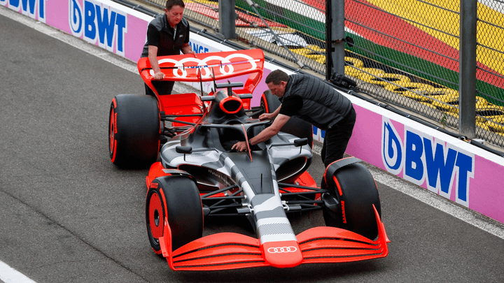 Une monoplace de Formule 1 Audi avec livrée grise et rouge en panne dur la pit lane