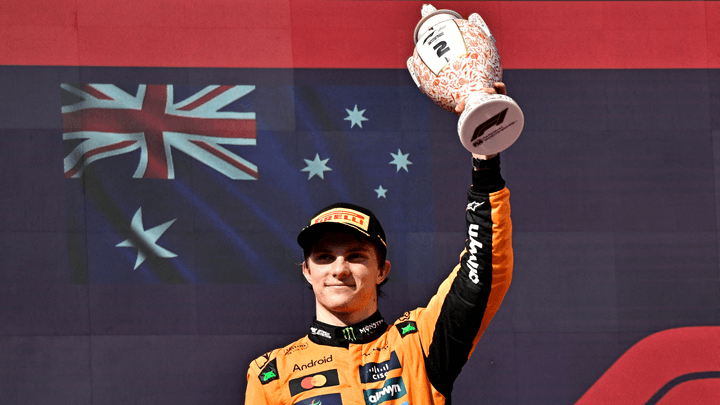 Oscar Piastri célèbre son podium avec son trophée au Grand Prix, le drapeau australien en arrière-plan