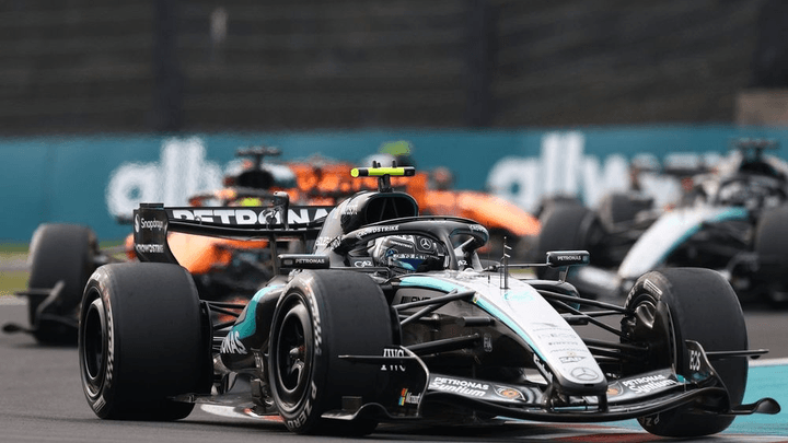 Voiture McLaren orange en tête d'un groupe de monoplaces de F1 en course sur circuit