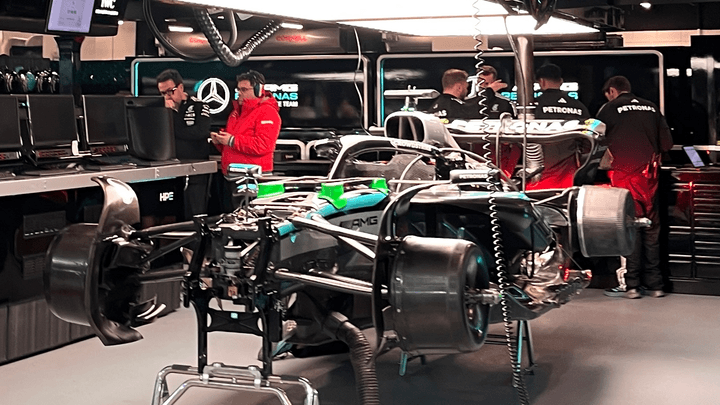 Mécaniciens Mercedes-AMG travaillant sur une monoplace F1 dans le garage avec logo Petronas