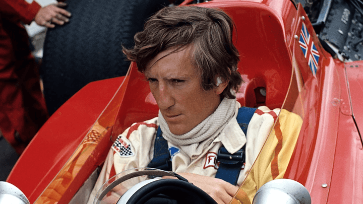 Pilote de F1 dans le cockpit d'une monoplace rouge avec drapeau britannique, années 70