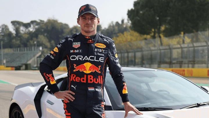Max Verstappen en combinaison Red Bull Racing Oracle posant avec une voiture blanche sur circuit