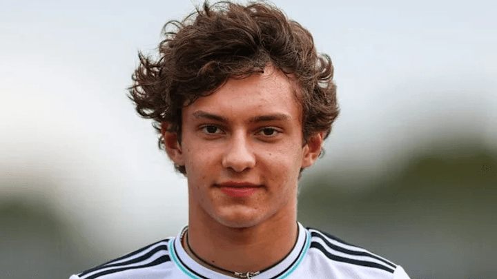 Portrait de Kimi Antonelli en tenue Mercedes, souriant avec ses cheveux bouclés caractéristiques