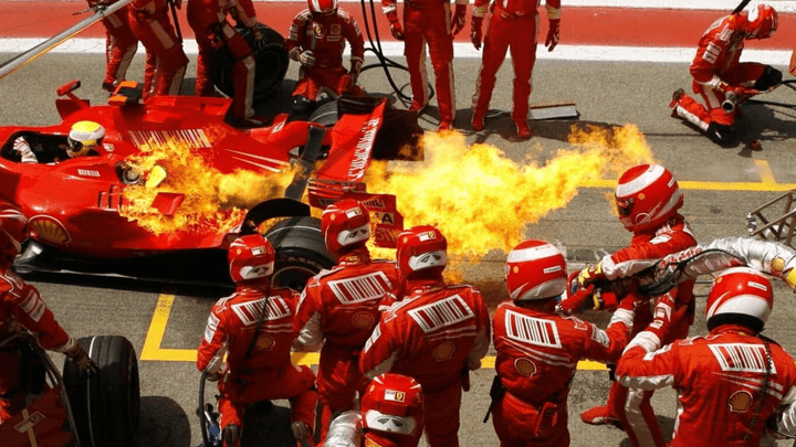 Incendie lors d'un arrêt au stand Ferrari, mécaniciens évacuant la monoplace en flammes
