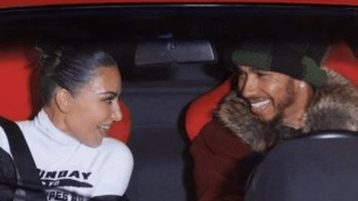 Couple souriant dans une voiture de sport rouge sur un circuit de Formule 1