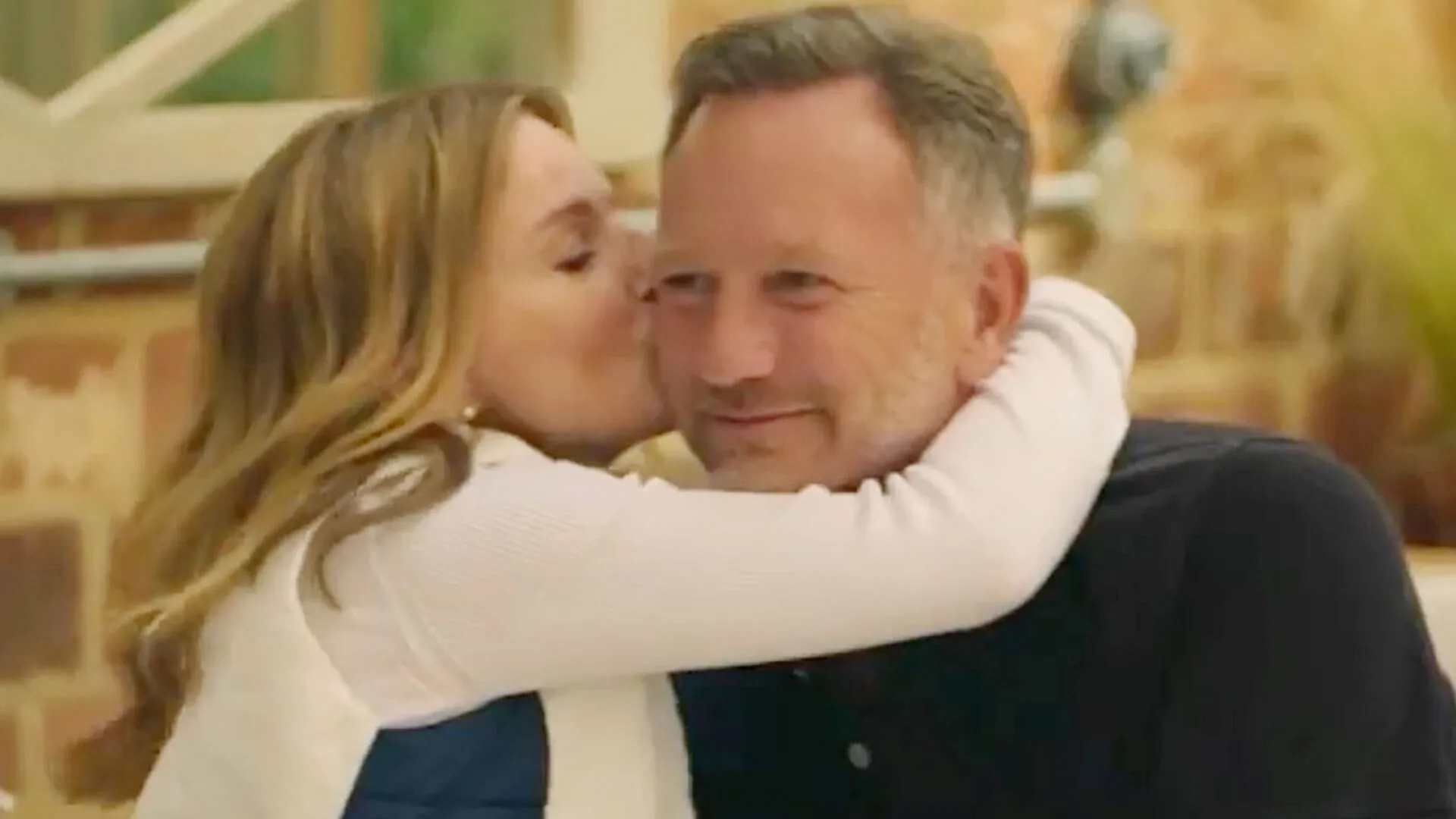 Accolade chaleureuse entre une femme blonde et un homme en costume dans un environnement décontracté