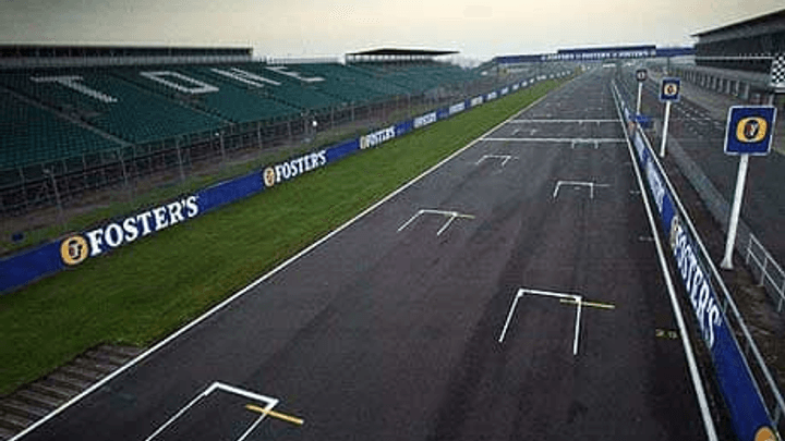 Ligne droite principale du circuit de Silverstone avec tribunes et publicités Foster's