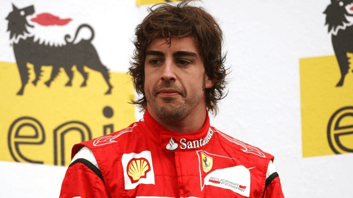 Fernando Alonso en combinaison Ferrari rouge sur le podium avec logos Shell et Santander