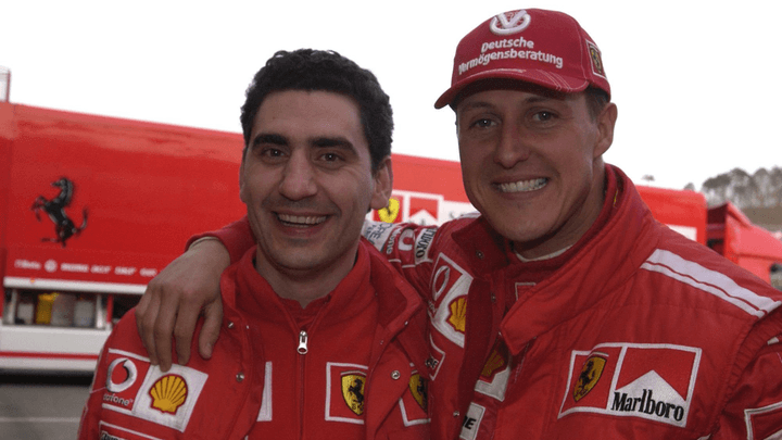 Michael Schumacher et un pilote Ferrari posent ensemble en combinaison rouge dans le paddock