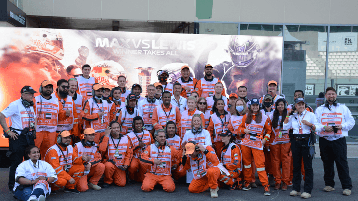 Photo de groupe des bénévoles de Formule 1 en tenue orange officielle lors d'un Grand Prix