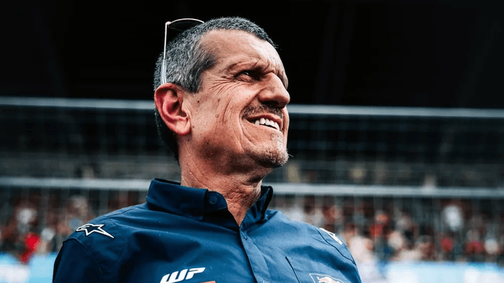 Membre de l'équipe de course souriant en combinaison bleue avec logos sponsors sur circuit