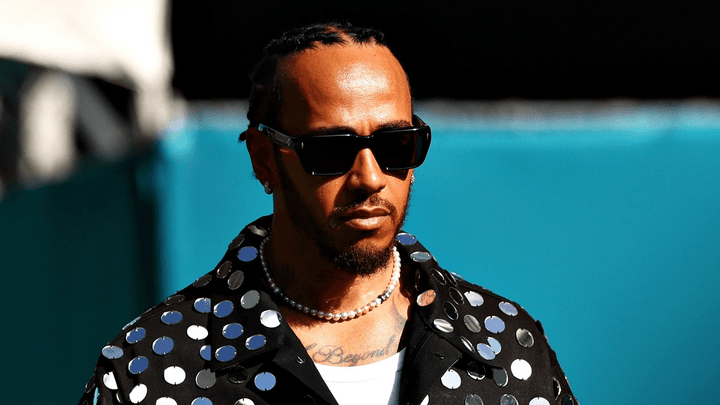Lewis Hamilton en veste à sequins noire et lunettes de soleil dans le paddock F1