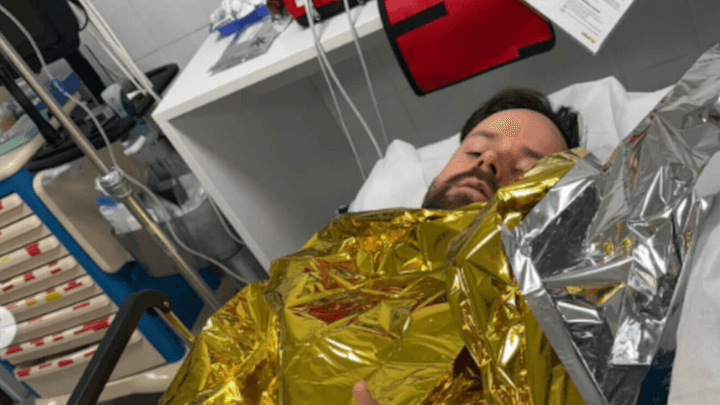 Pilote de course épuisé allongé sous une couverture de survie dorée après un effort intense