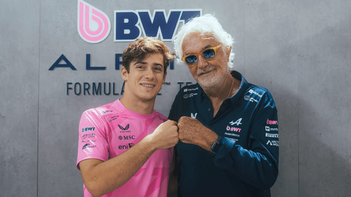 Pilote F1 en combinaison rose Alpine BWT posant avec Flavio Briatore devant logo équipe