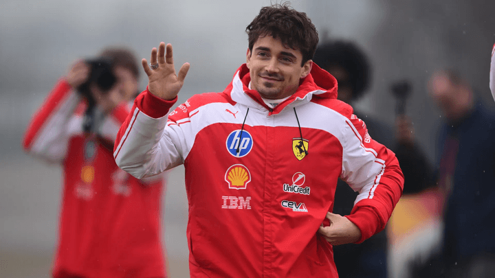 Charles Leclerc salue les fans en tenue Ferrari rouge et blanche lors d'un événement F1