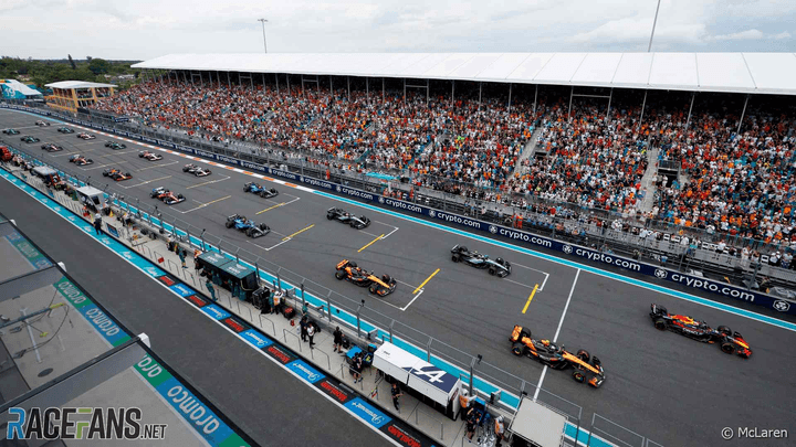 Vue aérienne de la grille de départ F1 avec les monoplaces alignées devant les tribunes bondées