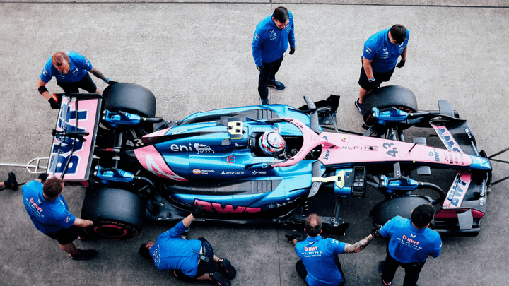 Vue aérienne de mécaniciens Alpine travaillant sur une monoplace de F1 dans les stands