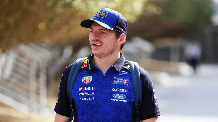 Pilote Red Bull Racing en polo bleu avec sponsors, casquette et sac à dos sur le paddock