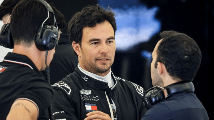 Sergio Pérez en combinaison Red Bull Racing en discussion avec son équipe dans le garage