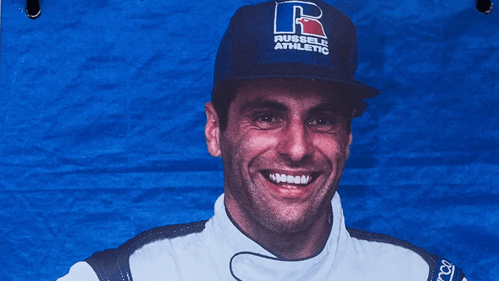 Roland Ratzenberger en combinaison de course blanche, souriant avec son casque Arai