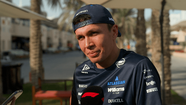 Pilote Williams F1 en combinaison d'équipe avec sponsors, casquette et sourire