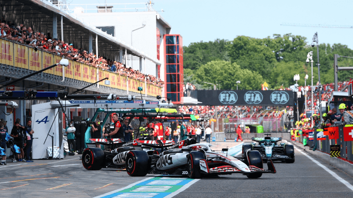 Monoplaces F1 dans la voie des stands avec équipes et spectateurs en arrière-plan