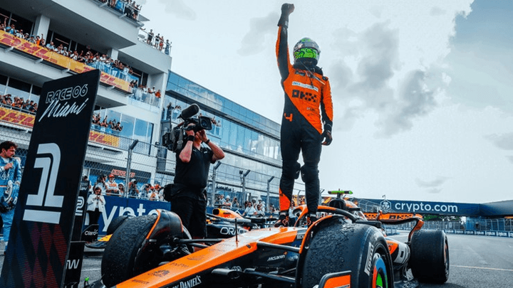 Pilote McLaren célébrant victoire debout sur monoplace orange, tribunes Miami GP