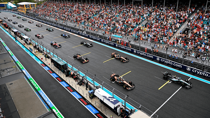 Grille de départ F1 avec monoplaces alignées devant gradins bondés de spectateurs