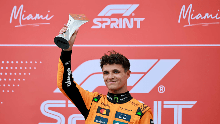 Lando Norris sur le podium du sprint de Miami, levant son trophée de vainqueur en combinaison McLaren orange