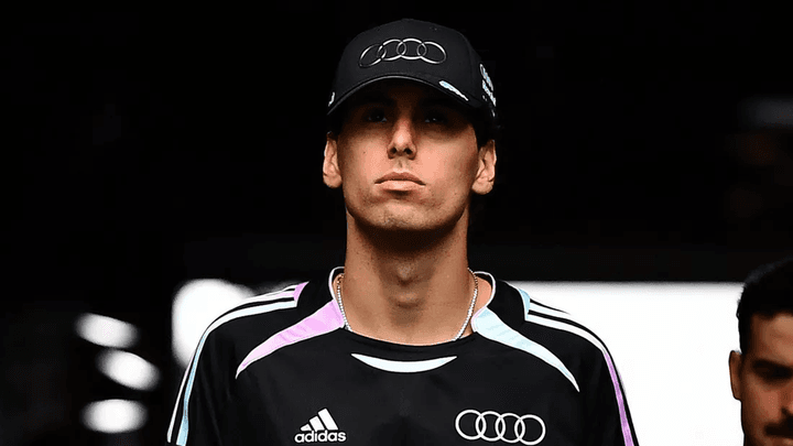 Pilote F1 en tenue Audi avec casquette et maillot Adidas/Revolut noir et violet