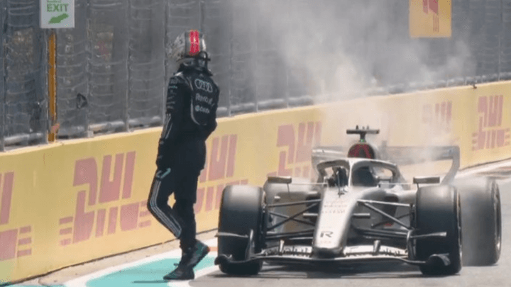 Pilote F1 sortant de sa monoplace fumante après un abandon ou incident sur le circuit