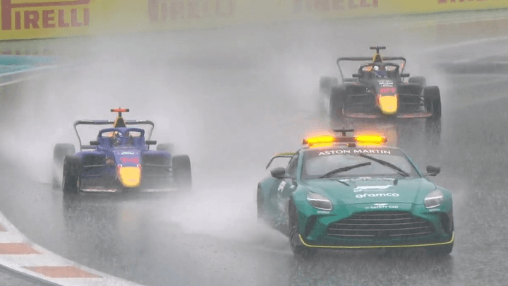 Safety car Aston Martin menant deux monoplaces F1 sous la pluie avec publicités Pirelli