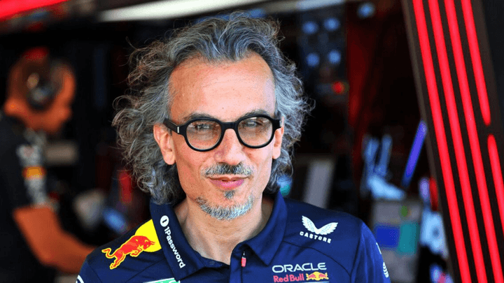 Homme aux cheveux gris bouclés et lunettes en polo Red Bull Racing dans le paddock F1