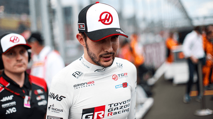 Pilote Haas F1 en combinaison blanche avec casquette d'équipe dans le paddock