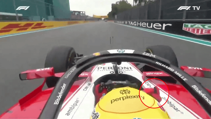 Vue onboard d'une Alfa Romeo F1 avec volant rouge et casque jaune sur circuit