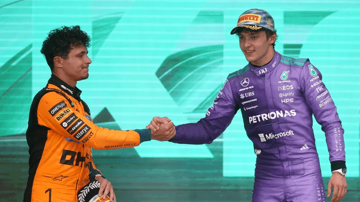 Poignée de main entre pilote McLaren en orange et pilote Mercedes en violet sur le podium
