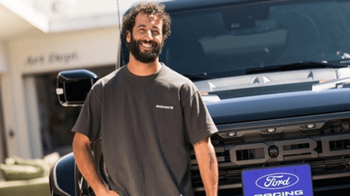 Daniel Ricciardo devant un véhicule Ford avec le logo de la marque visible