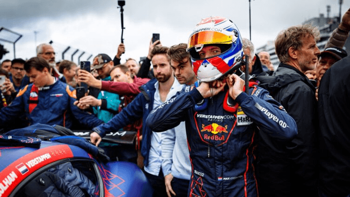 Pilote Red Bull F1 ajustant son casque tricolore avant la course, entouré de mécaniciens
